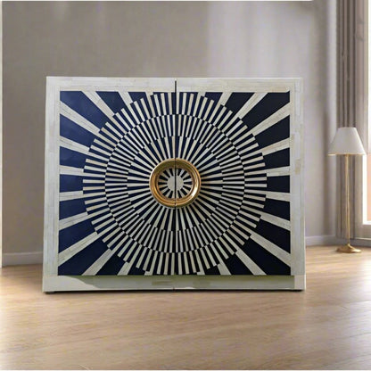 Art Deco-inspired black bar cabinet with white bone inlay patterning, two doors, and large circular gold-finished handles. The strong geometric contrast creates a sculptural statement while the cabinet offers concealed storage for spirits, glassware, or media essentials. This handcrafted indoor furniture piece is designed as a distinctive accent for eclectic and luxury interiors.