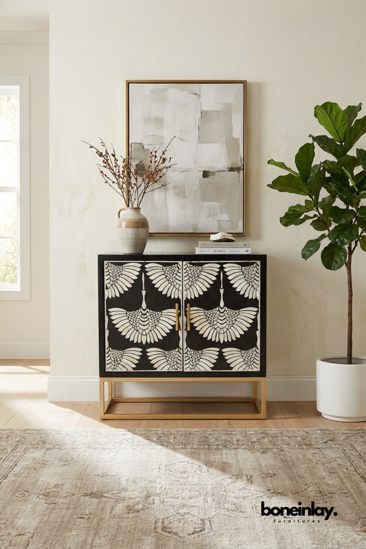 Black bone inlay cabinet with a striking crane wing feather pattern.
Two doors feature symmetrical bird motifs in bone inlay detailing.
Brass base frame gives the piece a refined, elevated look.
Styled beneath a framed abstract print and ceramic pitcher.