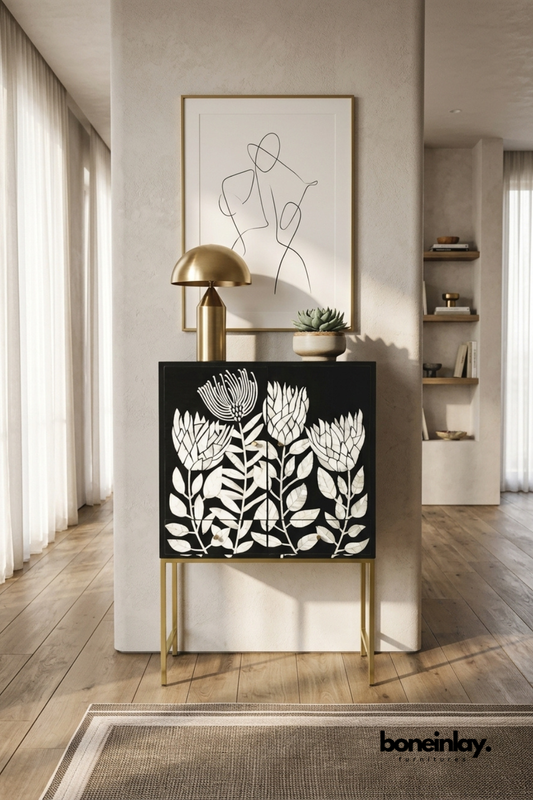 Black and white floral bone inlay bar cabinet with a botanical pattern.
Hand-cut bone inlay forms detailed leaf and flower motifs on two doors.
Slim brass metal legs give the piece a refined, elevated stance.
Styled as an entryway console with a brass lamp and framed line art.