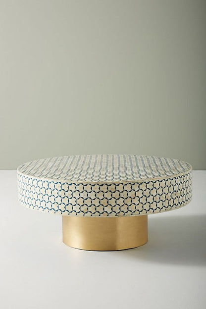 Front angle view of a round blue and white bone inlay coffee table with a geometric inlay surface and cylindrical brass base, showing the handcrafted Moroccan center table as a colorful living room furniture option.