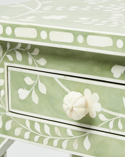 Detailed view of the drawer front on a sage green bone inlay console table featuring a hand-carved white bone flower knob and trailing vine and leaf inlay pattern