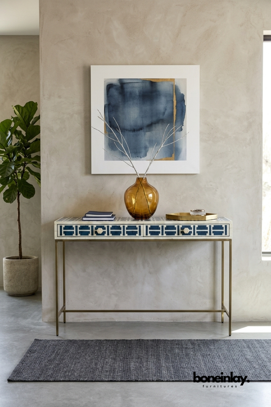 Navy blue and ivory bone inlay console table featuring a geometric pixel-style pattern across two drawers. Slim brass legs and hardware add a refined, airy contrast to the bold pattern. Styled with an amber glass vase, stacked books, and a brass catchall tray beneath framed watercolor art. A striking entryway console for eclectic and transitional interiors.