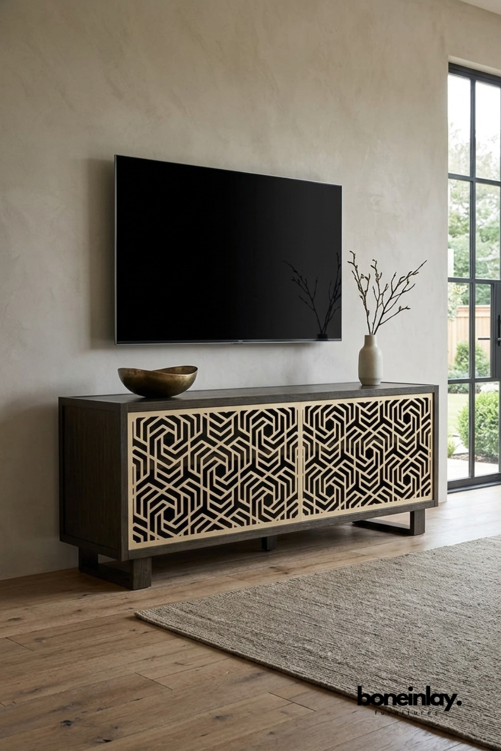 Modern dark wood TV console featuring intricate geometric bone inlay pattern on cabinet doors. Styled beneath a wall-mounted television in a minimalist living room with brass bowl and ceramic vase decor. Handcrafted design with block feet, ideal for contemporary and transitional home interiors. Perfect entertainment unit for adding textured visual interest to living spaces.