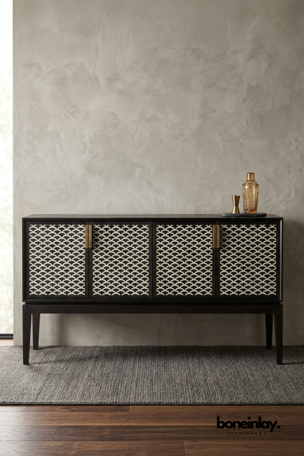 Black and white bone inlay bar cabinet featuring a scalloped fish-scale pattern across four cabinet doors. Brass tab handles and slim tapered wood legs complete the refined mid-century silhouette. Styled with a copper cocktail shaker, brass jigger, and crystal glass on a marble tray. A sophisticated bar cabinet for entertaining spaces and elegant dining room styling.