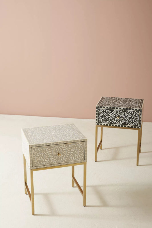 Pair of handmade bone inlay floral design nightstands in grey and dark colour options, featuring all-over vine leaf pattern and slim brass metal legs on a pink backdrop.