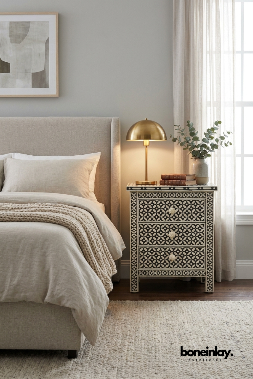 Handmade bone inlay geometric eye design nightstand in black and white beside a bed in a modern bedroom with gold lamp and neutral decor