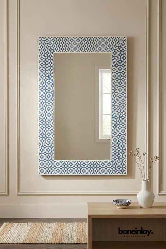 Navy blue and ivory bone inlay wall mirror featuring a repeating floral medallion pattern across a wide rectangular frame. Bold geometric border adds graphic pattern and rich color to any wall. Styled above a wood console table with a ceramic vase and small patterned bowl. A striking statement mirror for entryways, hallways, and eclectic interiors.
