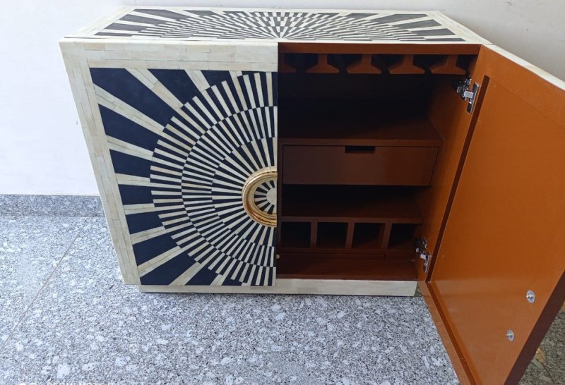 Black and white bone inlay bar cabinet featuring a geometric radial design, two cabinet doors, and oversized round gold-finished hardware.