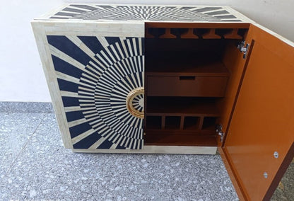 Black and white bone inlay bar cabinet featuring a geometric radial design, two cabinet doors, and oversized round gold-finished hardware.