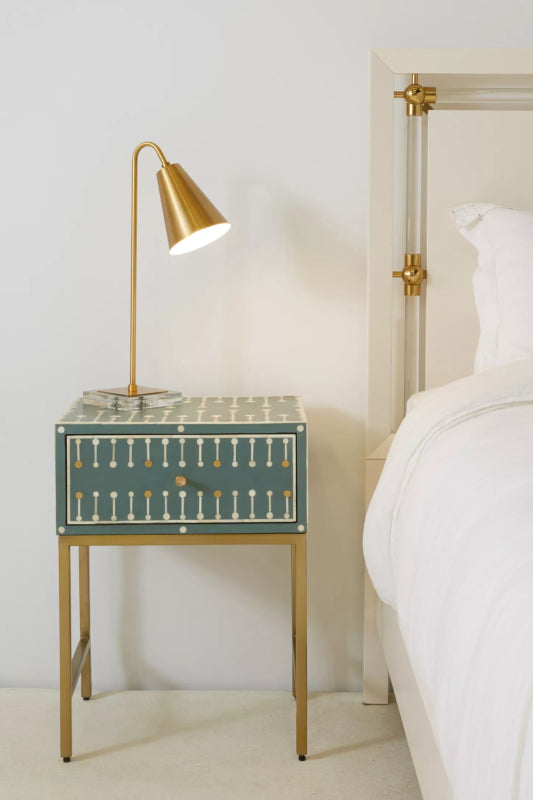 Handmade teal bone inlay nightstand with white and gold dot-dash pattern on brass metal legs, styled in a modern luxury bedroom with a brass reading lamp.