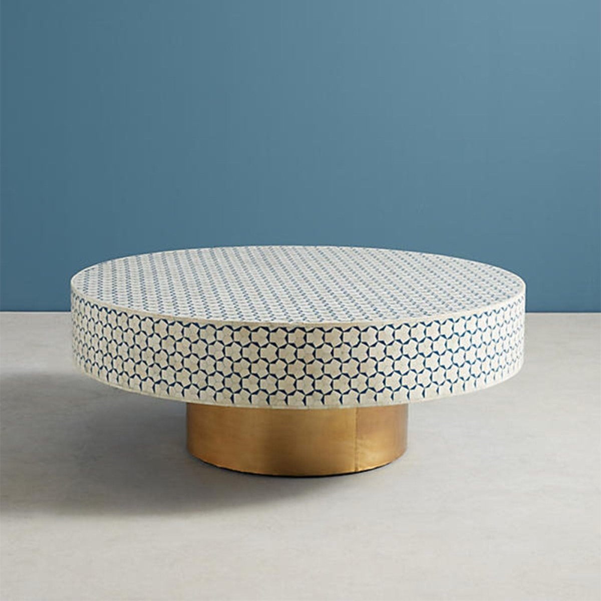 Overall product view of a round blue and white bone inlay coffee table with a geometric inlay tabletop and cylindrical brass base, showing the handcrafted Moroccan center table in its blue colorway for living room styling.