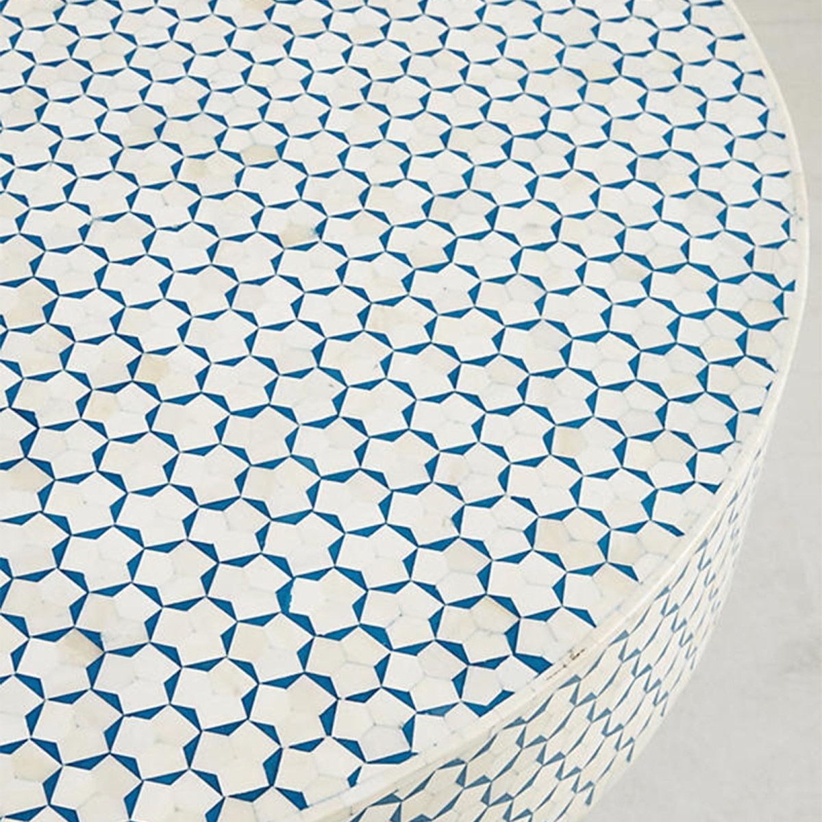 Close-up top view of the blue and white bone inlay coffee table, showing the circular tabletop with its repeating geometric inlay pattern, handcrafted bone surface, and contrasting blue color details clearly across the Moroccan design.