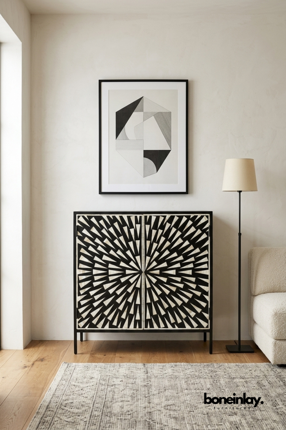 Handmade black and white bone inlay sunburst cabinet on iron legs styled in a modern living room with abstract wall art and floor lamp