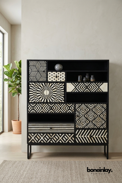 Black and white bone inlay curio cabinet featuring a striking patchwork of mixed geometric patterns across drawers and open shelving. Combines closed storage with display niches for books, sculptures, and decorative objects. Slim black metal legs complete the bold graphic silhouette. A dramatic statement cabinet for eclectic and maximalist living spaces.