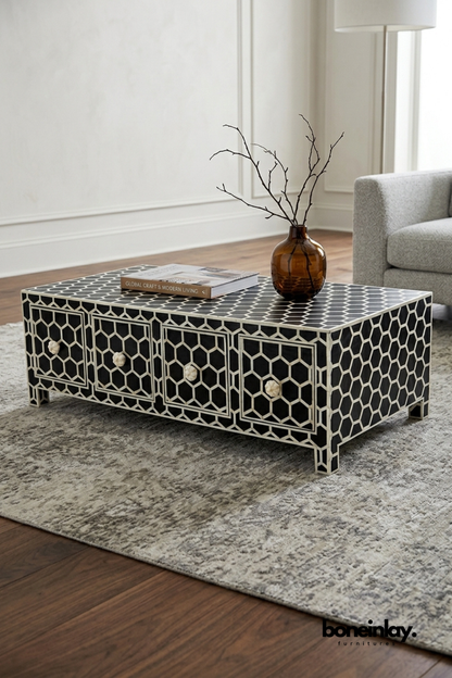 Black and white bone inlay coffee table featuring a geometric honeycomb pattern across four front drawers. Bone flower-shaped knobs and matching inlay legs complete the intricate handcrafted design. Styled with an amber glass vase and coffee table book on a plush textured rug. A striking storage coffee table for modern and eclectic living rooms.