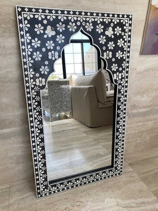 Handmade black bone inlay mirror frame with white floral and butterfly pattern, arch-shaped cutout, leaning against a living room wall