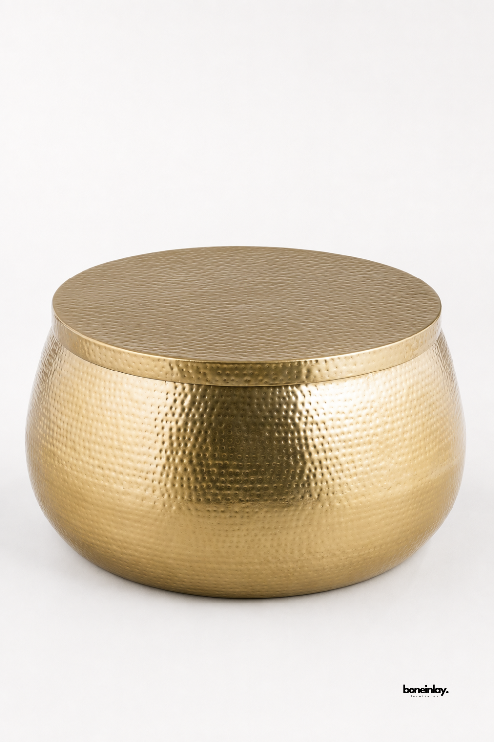 Artisan-crafted hammered brass drum coffee table showcasing a rounded spherical silhouette and fine hand-dimpled metal surface detailing. Displayed against a clean white studio backdrop, this versatile metallic center table offers durable solid construction, eye-catching texture, and timeless glamour for living room spaces.