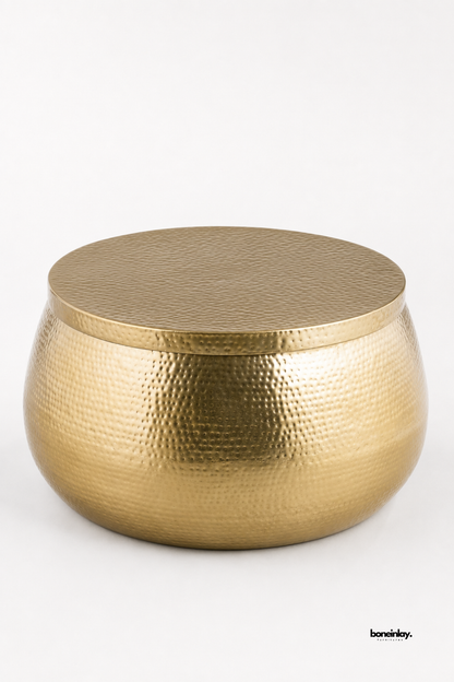 Artisan-crafted hammered brass drum coffee table showcasing a rounded spherical silhouette and fine hand-dimpled metal surface detailing. Displayed against a clean white studio backdrop, this versatile metallic center table offers durable solid construction, eye-catching texture, and timeless glamour for living room spaces.