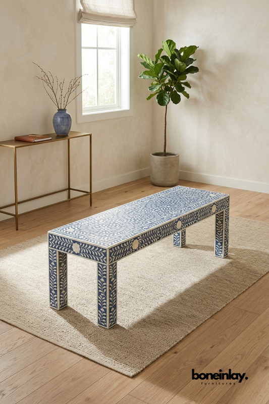 Navy blue and ivory bone inlay bench featuring an intricate floral vine pattern across the top and apron. Clean squared legs with matching inlay borders complete the tailored silhouette. Styled with a stoneware vase and dried branches near a brass console table and fiddle leaf fig. A versatile long coffee table or bench for eclectic living spaces.