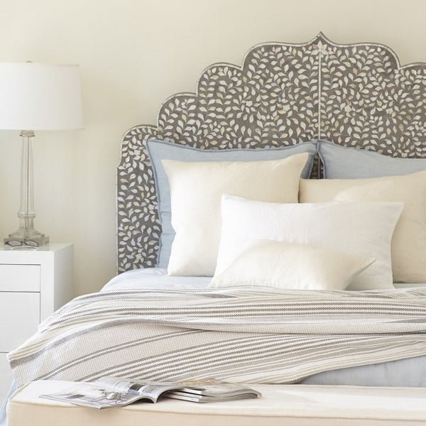 Bone inlay Mehrab headboard with scalloped silhouette styled in a neutral grey and white bedroom with layered white pillows