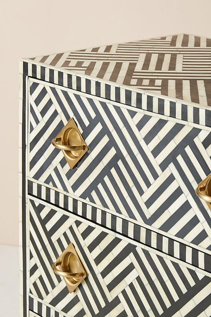 Close-up of two drawer fronts on a black and white optical bone inlay dresser featuring sculptural solid brass ring pull handles against the bold geometric stripe inlay pattern.