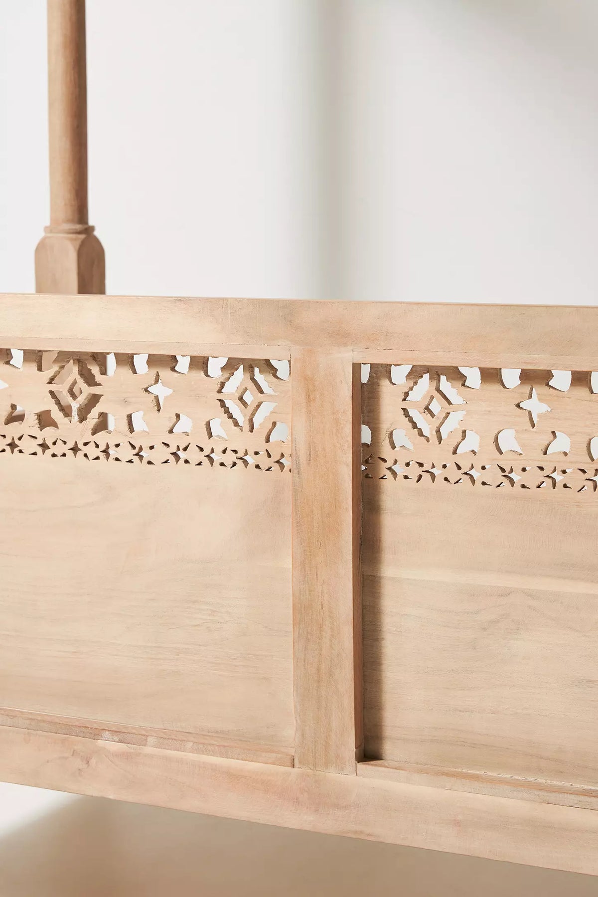 Indian-inspired wooden canopy diwan with intricate lattice backrest and natural timber finish.