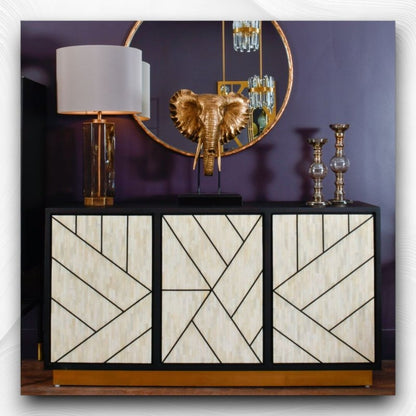Three-door ivory bone inlay credenza with bold black geometric line pattern on each door panel, matte black mango wood frame, and polished gold brass base strip.
