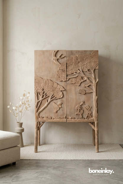 Land & Sky armoire in natural solid wood, featuring an expansive high-relief hand-carved scene of trees and birds across its tall cabinet doors.