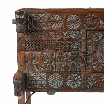 Lattice carved trunk chest in natural solid wood, front view of the left panel with figures and floral rosettes.