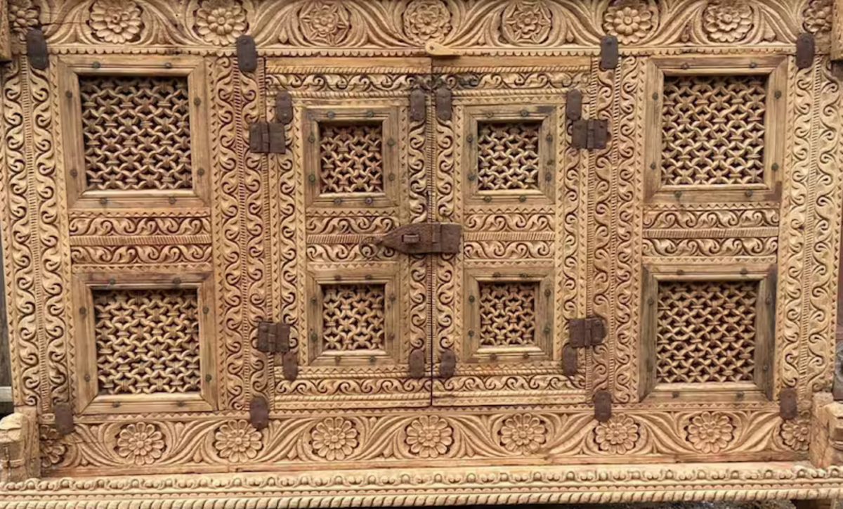 Pale wood credenza with carved panels and lattice doors, straight-on view against a plain light background.
