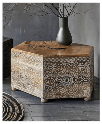 Light wood Albaron accent table in a front view, showing its carved face and decorative objects on top.