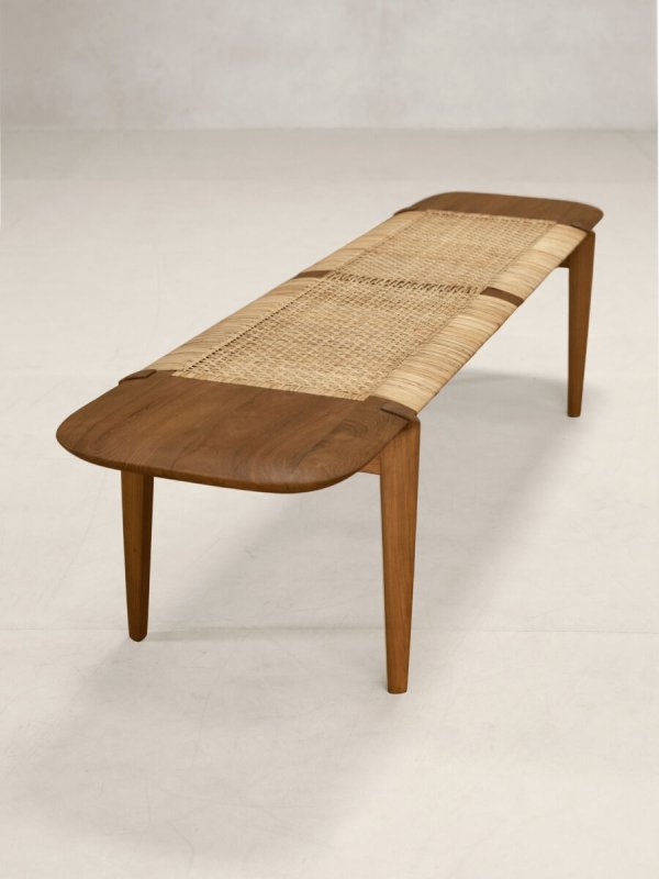 Long wooden cane bench with gently curved architectural frame, natural finish, and woven rattan seat.