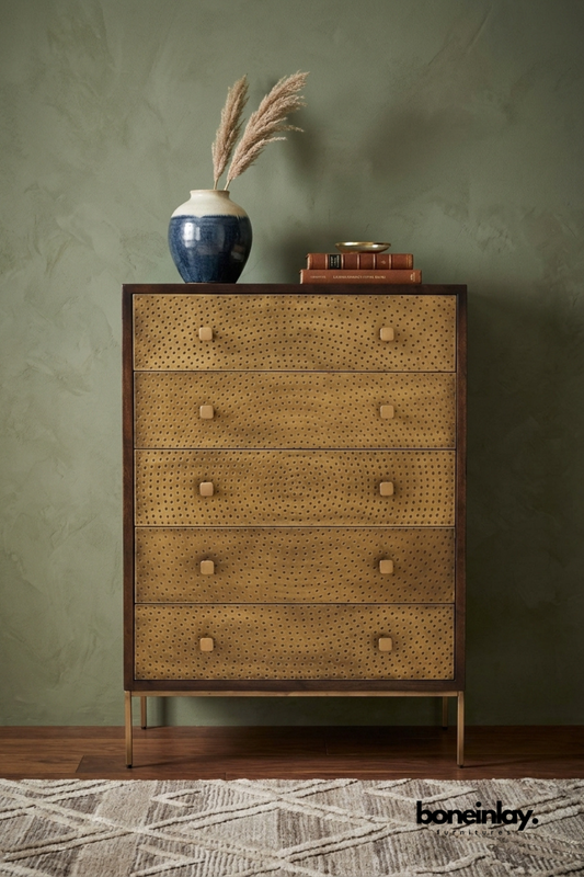 Handcrafted brass embossed tall chest of drawers with five spacious drawers, textured metal fronts, solid wood frame, slim brass legs, and contemporary bedroom storage furniture.