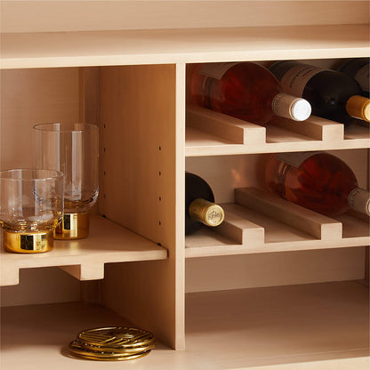 Marble top wine cabinet interior close-up, showing wine bottle slots and a glass tumbler shelf with brass coasters.
