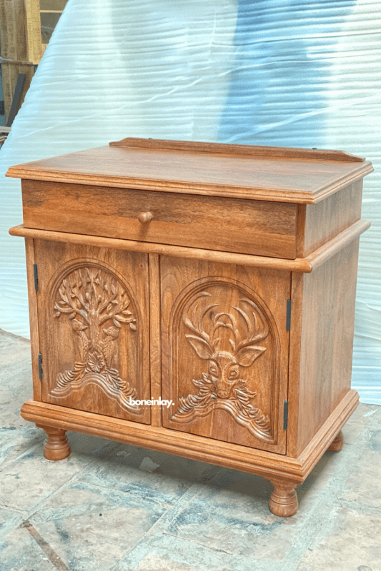 Menagerie carved accent cabinet in natural wood, angled front view showing the right side, tree and stag relief doors.