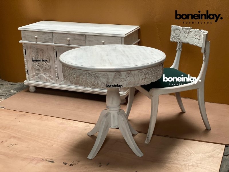 Menagerie White pedestal table set in rustic solid wood, front view showing the round carved apron and one green-seated chair.