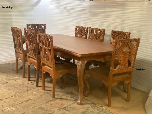 Menagerie wood dining table set in warm brown wood, side profile view showing carved chair backs and animal-shaped legs.