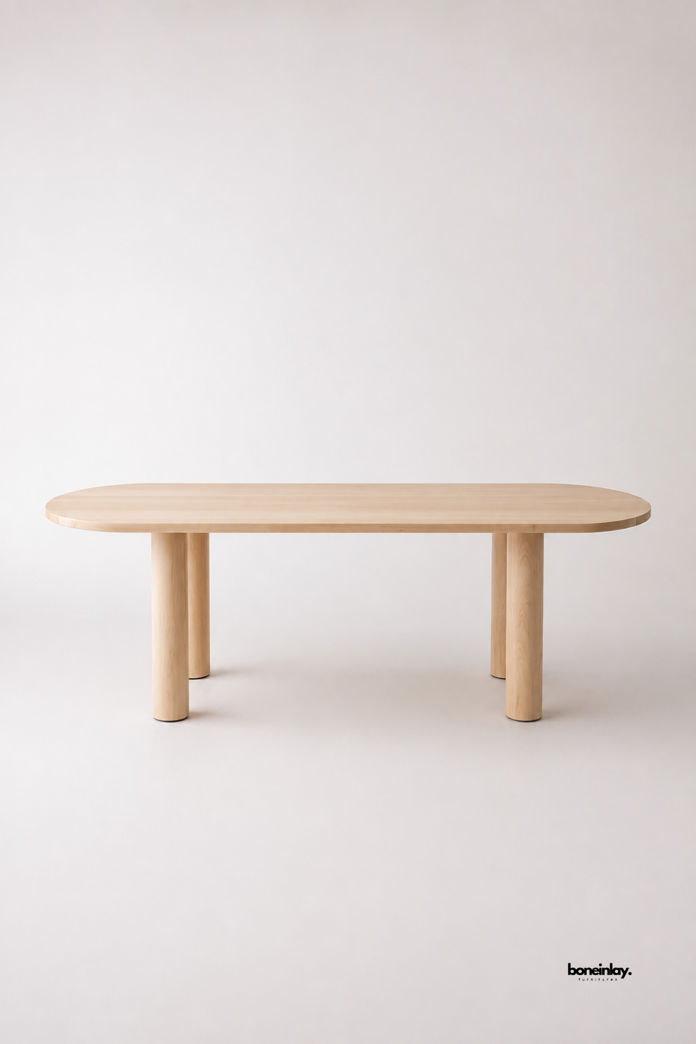 Artisan-crafted light natural oak oval dining table showcasing chunky round post legs and clean pill-shaped contours against a soft white background. This versatile wooden conference and dining table offers timeless minimalist aesthetics and sturdy craftsmanship for modern dining spaces.