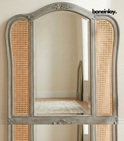 Decorative mirror with wicker backrest and wooden frame on a neutral background