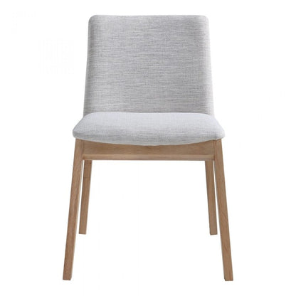 Front view of a modern minimalist dining chair with light wood legs and grey fabric upholstery against a white background.