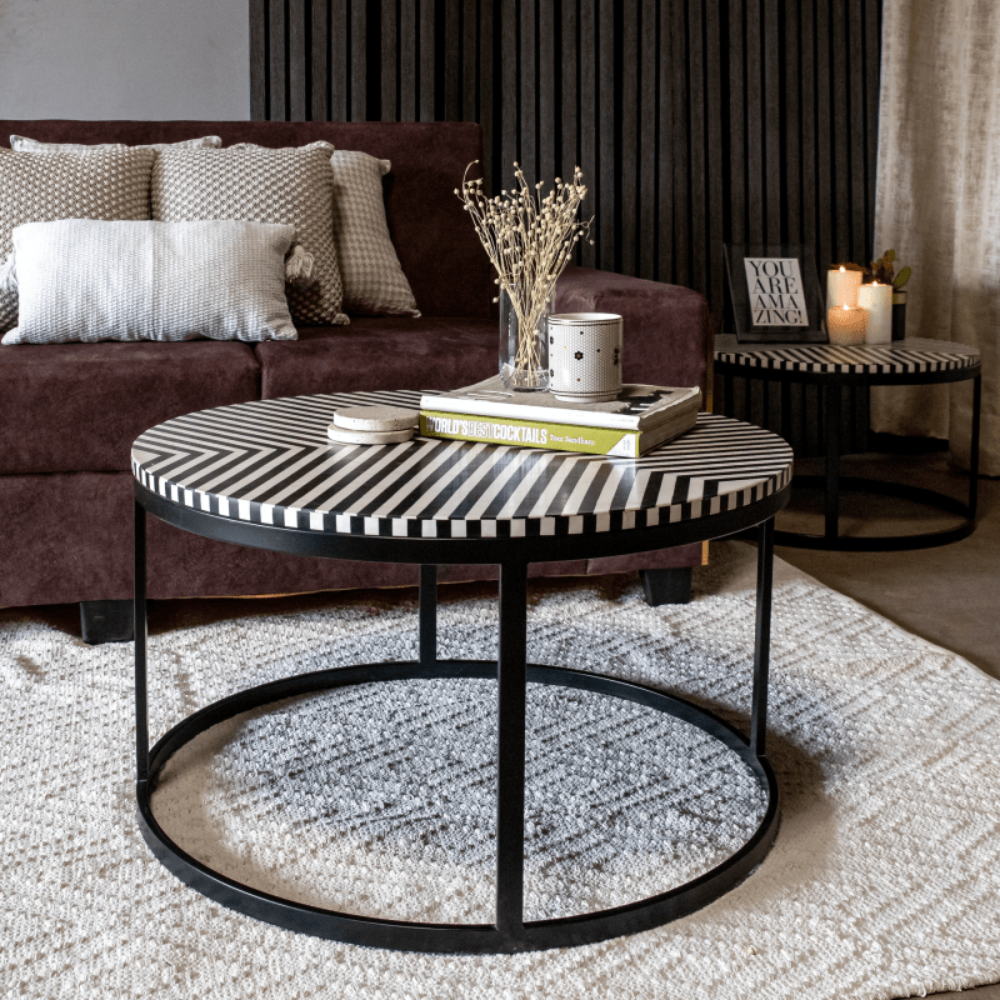 Monochrome bone inlay round coffee table styled in a moody dark living room with a matching side table, black metal base, geometric stripe handcrafted furniture