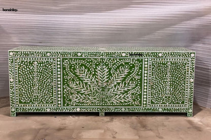Front view of a large olive green and white mother of pearl 4-door sideboard featuring an intricate central peacock and floral tree of life pattern against a textured workshop floor.