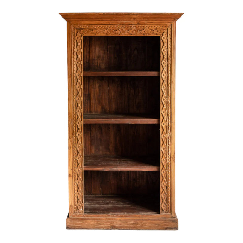 Natural wood bookshelf, front view showing its tall open frame, four shelves and carved border against a white wall.