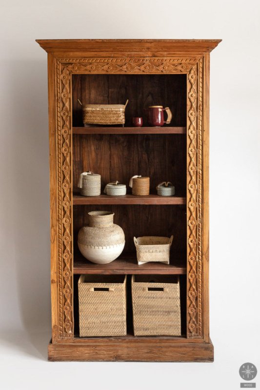 Natural wood display shelf, styled in a living room with books and decorative objects arranged on its open shelves.