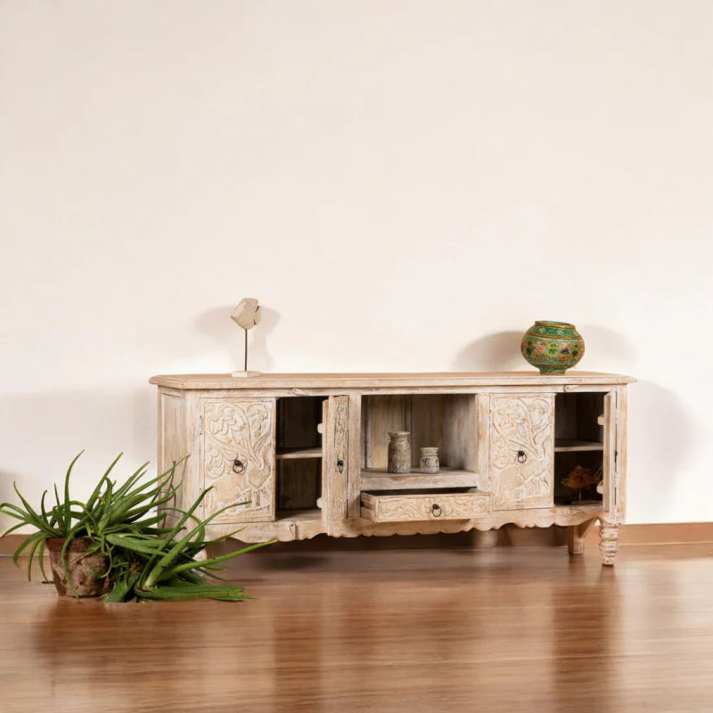 Natural Wood Entertainment Center styled in a living room with a TV above the carved cabinet and plants nearby.