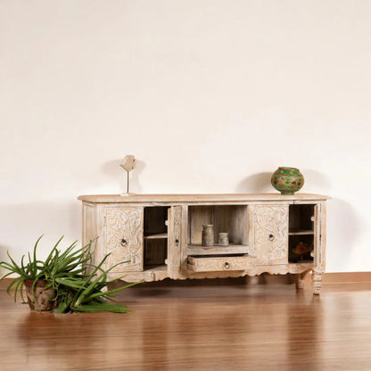 Natural Wood Entertainment Center styled in a living room with a TV above the carved cabinet and plants nearby.