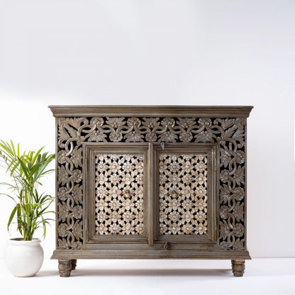 Natural wood floral buffet, front view showing two pierced flower doors, carved vine surrounds and short turned feet.

