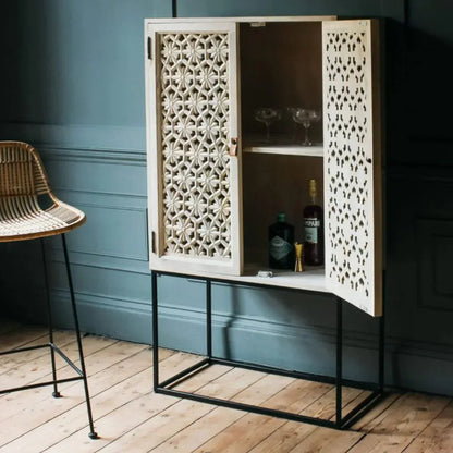 Natural wood storage cabinet standing on a black metal base, shown in a side profile view beside a chair.