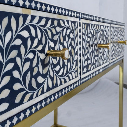 Navy bone inlay entryway table with white leaf inlay detailing on drawer fronts, brass knob handles, and slim gold metal frame legs