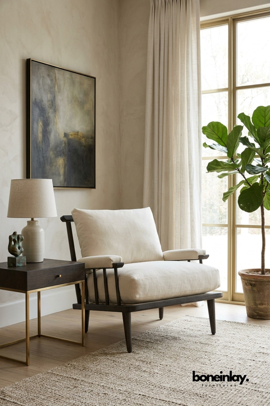 Black wood spindle-frame lounge chair with a low profile design.
Soft ivory linen seat and back cushions for added comfort.
Tapered wood legs give it a mid-century modern look.
Styled beside a wood and brass side table in a cozy corner.